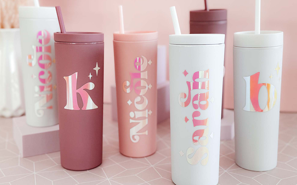 Six 18 oz. tumblers in white, blush pink, and dusty rose colors with reflective, iridescent text that says nicole, sarah, and monogrammed letter "k".